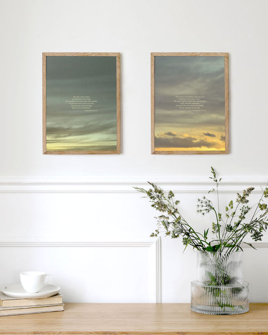 Two framed artworks with Lamentations 3:21-26 on a wall above a wooden table with a vase of flowers.