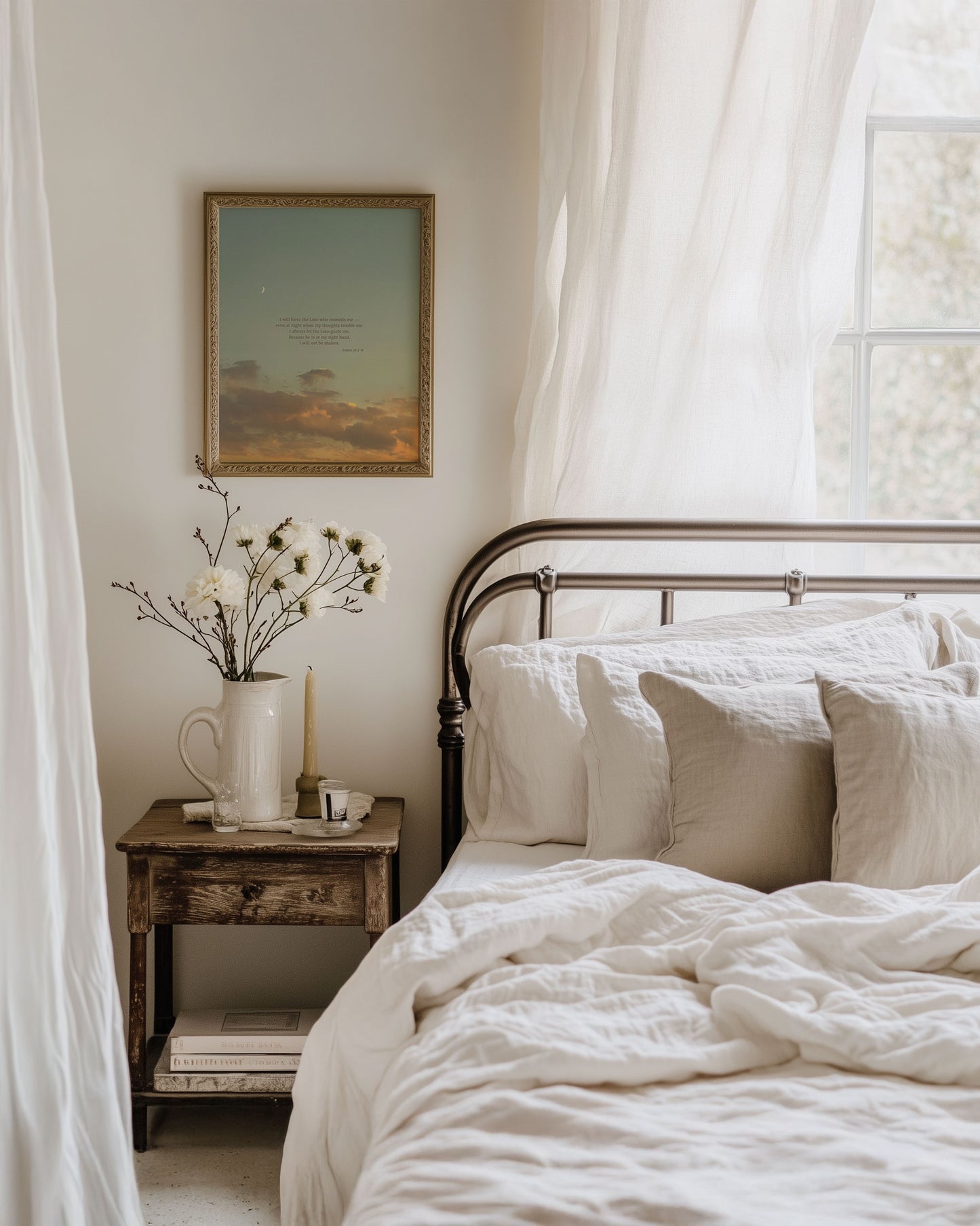 Framed Scripture art print of Psalm 16:7-8 on a blue sunset sky with soft golden/orange clouds and a crescent moon at the top left. The print is hanging on a wall in a cozy bedroom with a bed, nightstand and soft sunlight coming through a window behind the bed to the right of the image.