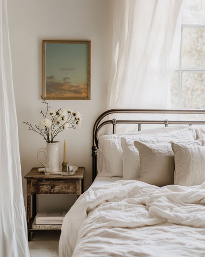 Framed Scripture art print of Psalm 16:7-8 on a blue sunset sky with soft golden/orange clouds and a crescent moon at the top left. The print is hanging on a wall in a cozy bedroom with a bed, nightstand and soft sunlight coming through a window behind the bed to the right of the image.